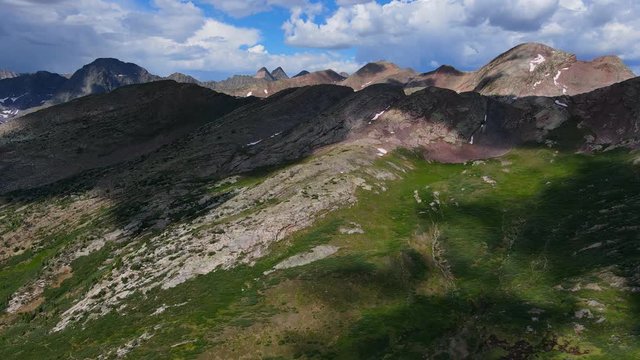 Aerial view Tilting down shot, Scenic view, Ridge of Red Mountain In San Juan Mountain Range in Colorado, Clouds Shading parts of the mountain in the background.
