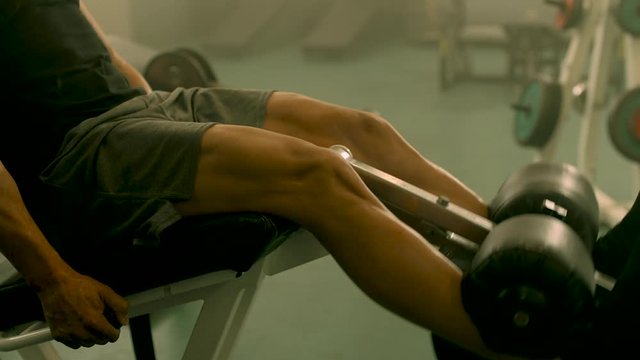 Closeup strong man having legs training at gym. Unrecognizable bodybuilding man making leg extension in sport club. Unknown male athlete workout in fitness center