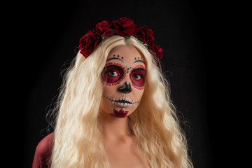 Woman with sugar skull makeup and blond hair isolated on black background. Day of the dead.