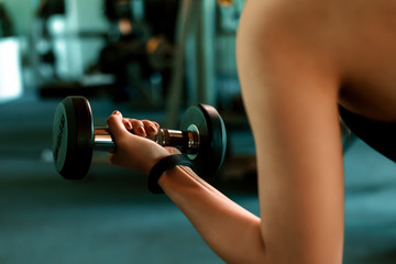 Fitness girl lifting dumbbell in fitness gym. Fitness workout and muscle concept.