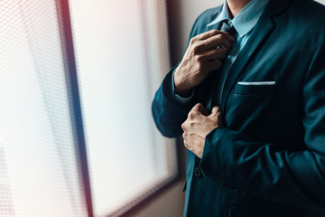 Businessman ware suit and adjusting necktie.