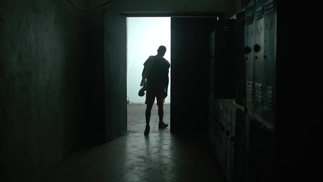 Back view young shirtless muscular Caucasian man hitting locker with his fist, tired and upset after failure in gym. Athletic weight lifter sportsman knocking on locker door overwhelmed after exercise
