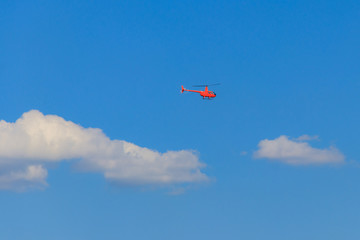 Flying orange helicopter in blue sky