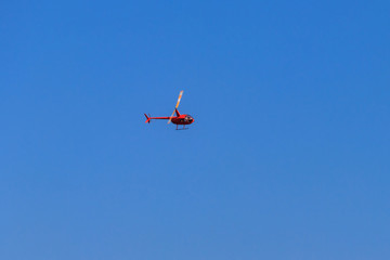 Flying orange helicopter in blue sky