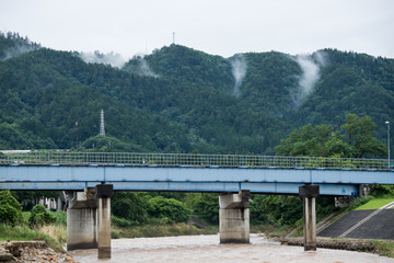 梅雨時期の山と橋と川の風景