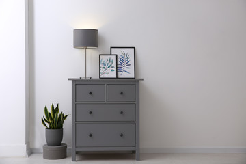 Grey chest of drawers in stylish room interior. Space for text