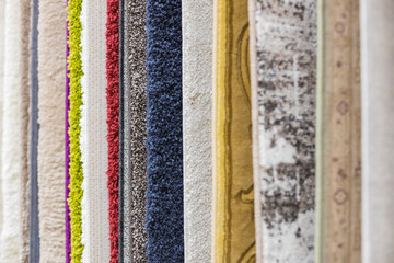 The store sells samples of various colorful rugs.