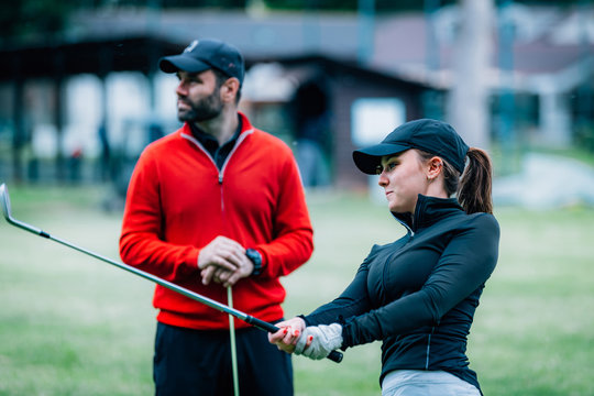 Golf Instructor Working With Young Woman On Swing Improvement