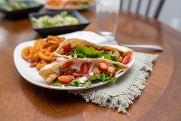 Chicken souvlaki  pita with Tzatziki, Greek style sandwich served with salad and curly fries.  