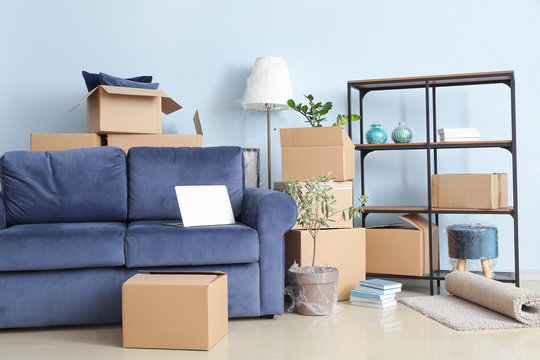 Cardboard boxes with belongings and sofa in new flat on moving day