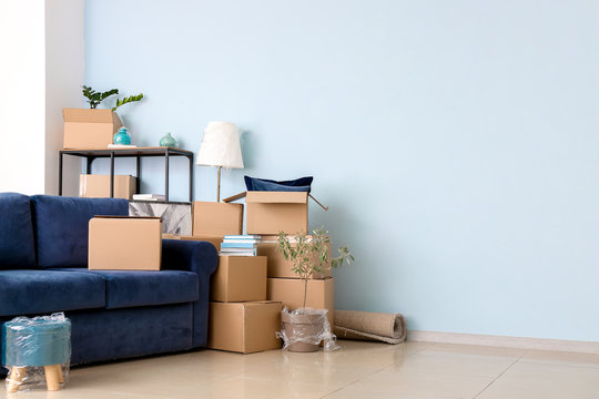 Cardboard boxes with belongings and sofa in new flat on moving day