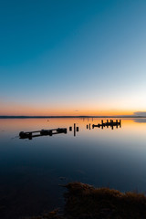 A broken wooden pier on the lake at sunrise time, Gorokan, Australia.