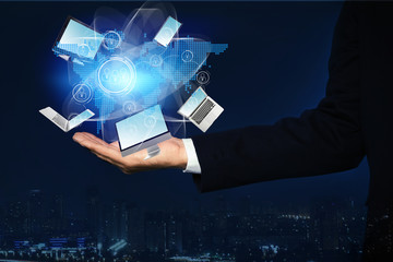 Young businessman holding different devices in hand and cityscape on background, closeup