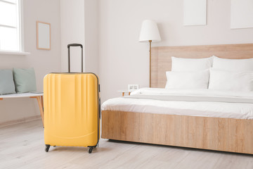 Suitcase near bed in hotel room
