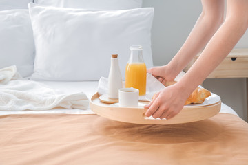Fototapeta na wymiar Chambermaid putting tasty breakfast on bed in hotel room