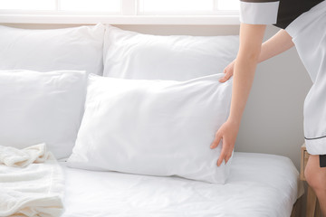 Chambermaid making bed in hotel room