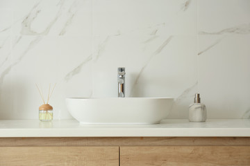 Obraz na płótnie Canvas Bathroom counter with sink, soap dispenser and reed air freshener