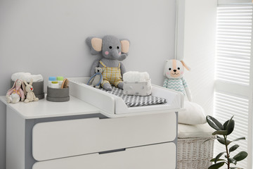 Fototapeta na wymiar Changing tray and pad on chest of drawers in baby room. Interior design
