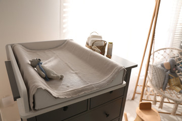 Chest of drawers with changing pad and tray in nursery. Baby room interior design