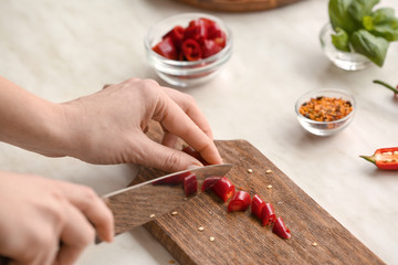 Woman cutting hot chili pepper, closeup