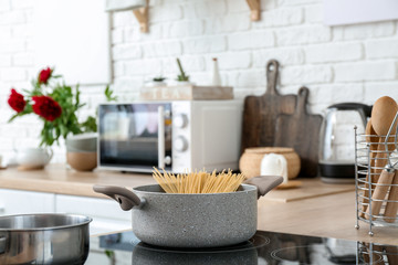 Saucepan with uncooked pasta on stove in kitchen