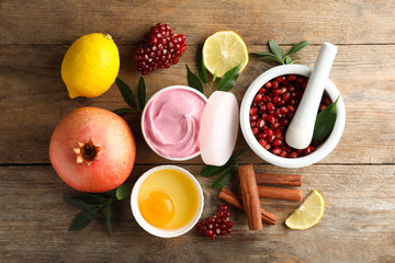 Flat lay composition with natural homemade mask, pomegranate and ingredients on wooden table