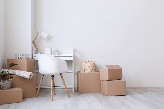 Cardboard boxes with belongings and table in new flat on moving day