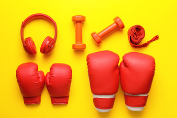 Different sports equipment with headphones on color background