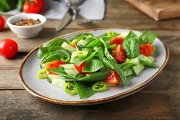 Plate with tasty cucumber salad on table