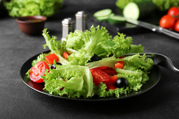 Plate with tasty cucumber salad on dark background