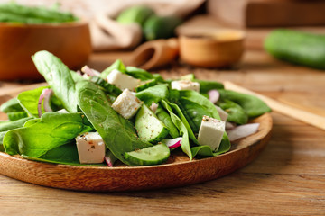 Plate with tasty cucumber salad on table