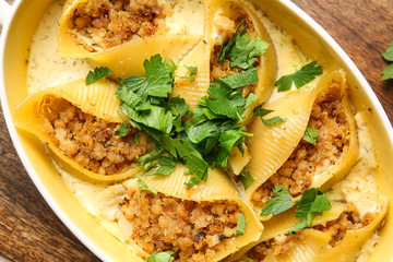 Baking dish with tasty conchiglioni pasta, closeup