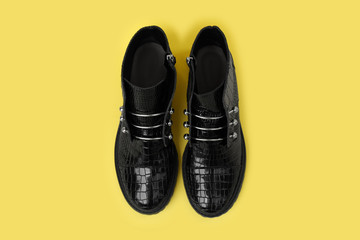 Pair of stylish ankle boots on yellow background, top view
