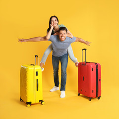 Happy couple with suitcases for summer trip on yellow background. Vacation travel