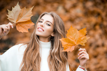 Woman with autumn leaves. Girl with orange leaves. Season and autumn holiday. Beauty and fashion. Smiling model with stylish hair.