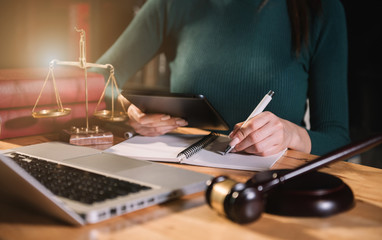 Justice and law concept.Judge in a courtroom the gavel, working with digital tablet computer on wood table in sun light.