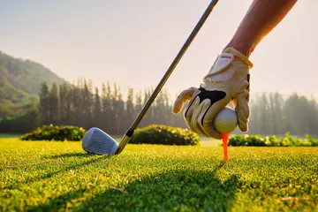 Fotobehang Close-up Hand Aziatische vrouw golfbal zetten tee met club in golfbaan op zonnige dag voor gezonde sport. Levensstijlconcept. © tonjung