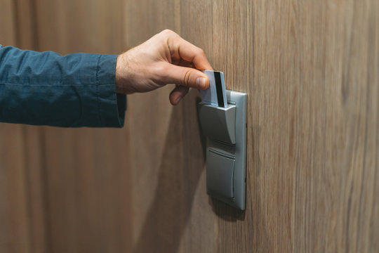 Adult man in blue jacket uses hotel card in the hotel room