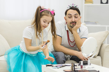 Fototapeta premium Photo of little girl applying makeup with her father.