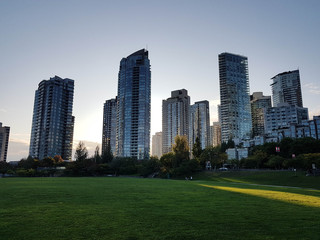 Fototapeta na wymiar Park view in Vancouver with tall apartment buildings and clear sky.