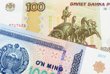 A macro image of a Russian one hundred ruble note paired up with a blue, white and green ten thousand som note from Uzbekistan.  Shot close up in macro.