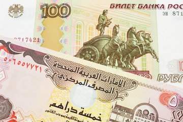 A macro image of a Russian one hundred ruble note paired up with a colorful five dinar bank note from the United Arab Emirates.  Shot close up in macro.