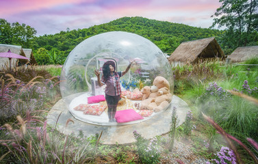 Beautiful girl in transparent camping tent called bubble tent or garden dome to enjoy in the jungles