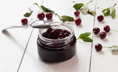 Cherry homemade jam and fresh cherries on a on a white wooden boards