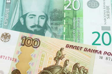 A macro image of a Russian one hundred ruble note paired up with a green and white twenty dinar...