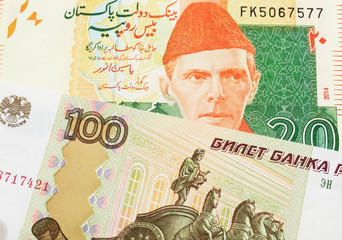 A macro image of a Russian one hundred ruble note paired up with a orange and green 20 rupee note from Pakistan.  Shot close up in macro.