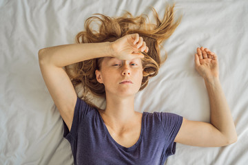 Fototapeta premium Extremly tired young woman lying on the bed, home alone. self-isolation at home, quarantine due to pandemic COVID 19. Mental health problems in self-isolation at home