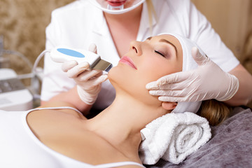 Obraz na płótnie Canvas cosmetology and beauty concept - close up of beautiful woman receiving ultrasound cavitation facial peeling