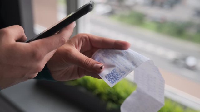Scanning QR code with smart phone. The woman reads the bar code using the application on the smartphone at home