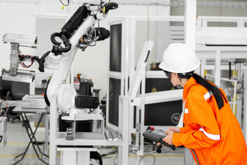 Engineer setting up automatic robot arms in smart factory.